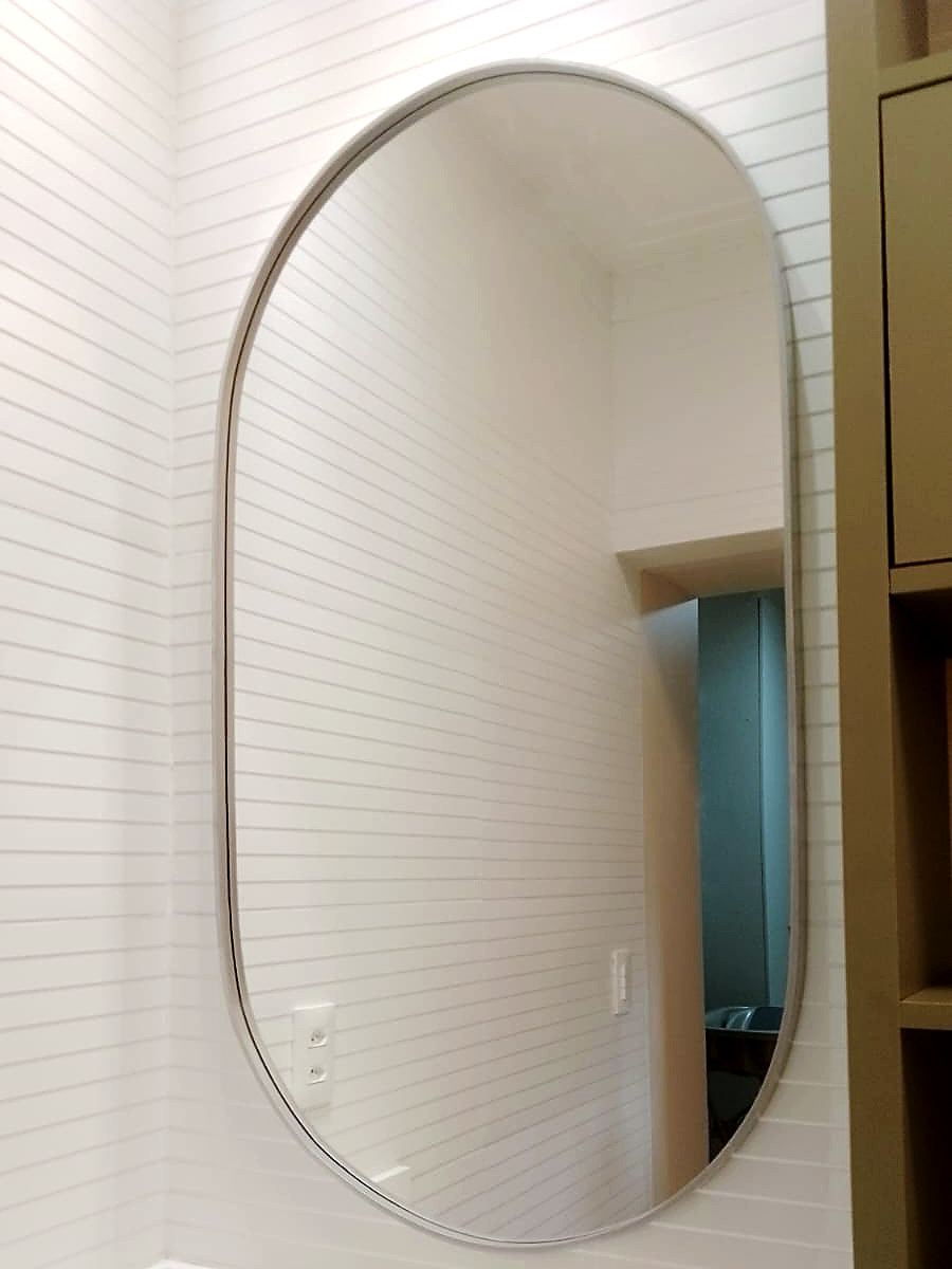 Detalhe de espelho oval com moldura de alumínio